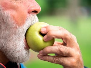 idoso comendo maçã